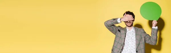 Positive Model Jacket Covering Eyes Holding Speech Bubble Yellow Background — Stock Photo, Image