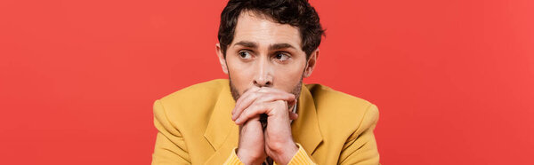 thoughtful man with clenched hands looking away isolated on red coral background, banner  