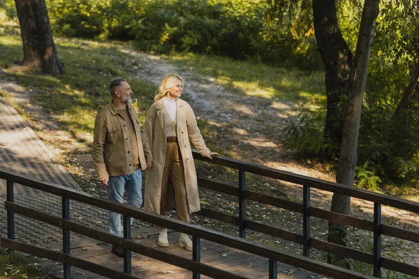 身着春装的年轻夫妇在公园的桥上漫步 — 图库照片