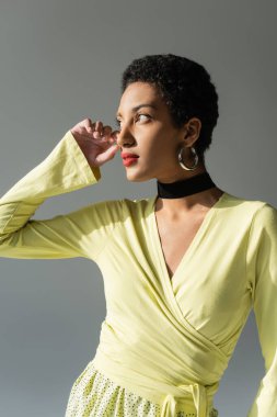 Güzel bir Afrikalı Amerikan modelinin portresi. Gri üzerine güneş ışığıyla izole bir şekilde bakıyor.