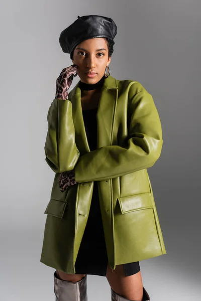 トレンディアフリカ系アメリカ人女性で手袋で動物のプリントとグレーに隔離された革のコート — ストック写真