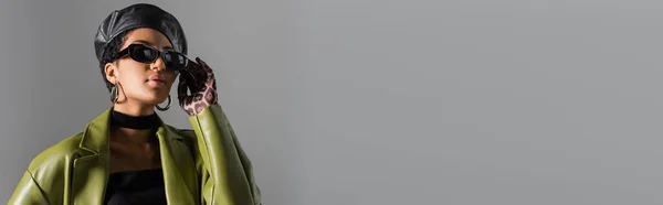 Стильная Африканская Американка Кожаном Берете Касается Солнцезащитных Очков Изолированных Сером — стоковое фото