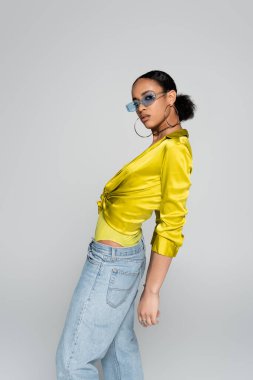 Mavi güneş gözlüklü Afro-Amerikan modeli. Gri renkli kameraya bakıyor. 