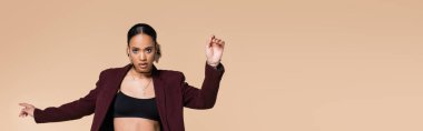 young african american woman in crop top and trendy maroon blazer posing isolated on beige, banner  clipart