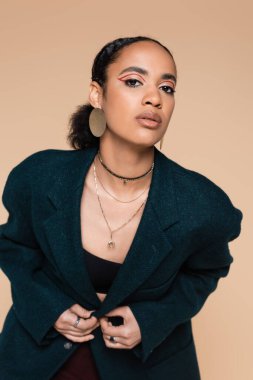 Koyu mavi yün ceketli, bej rengi ceketli genç Afro-Amerikan modeli. 