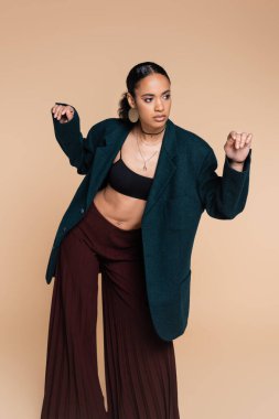 Koyu mavi yün ceketli genç Afro-Amerikan modeli bej rengi jest yapıyor. 