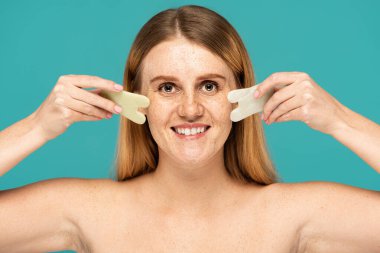 Turkuazda izole edilmiş yeşim yüzlü çilli neşeli kadın.
