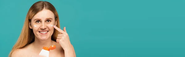 Счастливая Женщина Веснушками Держа Трубку Нанесение Косметического Крема Изолированы Бирюзовый — стоковое фото