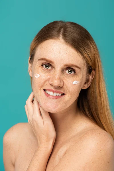 Glimlachende Vrouw Met Sproeten Cosmetische Crème Gezicht Geïsoleerd Turquoise — Stockfoto