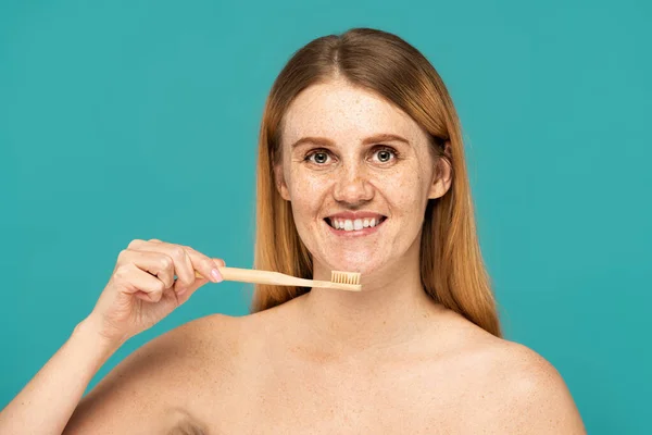 满脸雀斑 红头发的女人笑着拿着用绿松石隔开的牙刷 — 图库照片