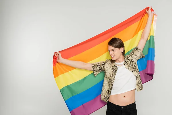 快乐而时尚的泛性别者 站在彩虹的旗帜下 孤零零地凝视着灰色的远方 — 图库照片