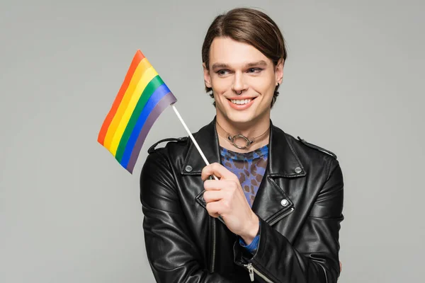 happy and stylish pansexual person in black leather jacket holding small lgbt flag isolated on grey