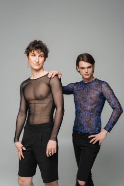 biseksüel model hayvan baskısı üstte. Gri renkte izole edilmiş moda partneri yakınında kameraya bakıyor.