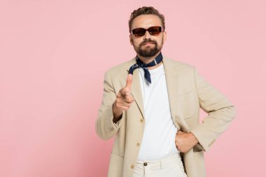 Boyunluk ve güneş gözlüklü şık Fransız adam pembe kameraya bakıyor. 