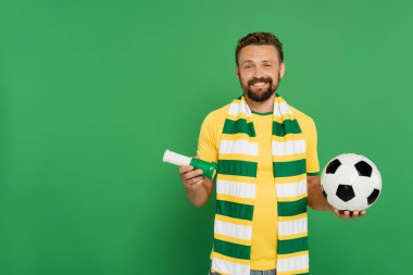 happy soccer fan holding sports horn and football isolated on green  clipart