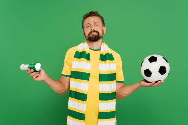 Spor kornosu tutan sakallı futbol fanatiği ve yeşil alanda izole edilmiş futbol topu 