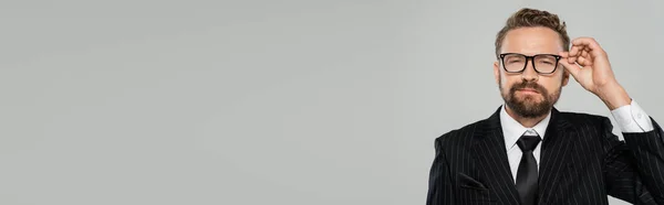 Бородатый Бизнесмен Формальной Одежде Регулируя Очки Глядя Камеру Изолированы Сером — стоковое фото