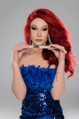 Gri renkte aplikatörlü rimel tutan şık bir travesti.  