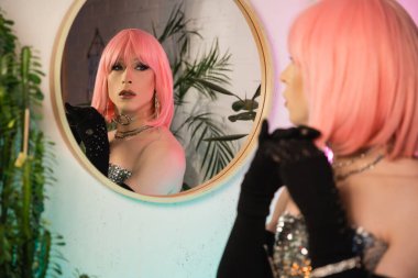 Üstte şık bir travesti ve evde aynaya bakan eldivenler. 