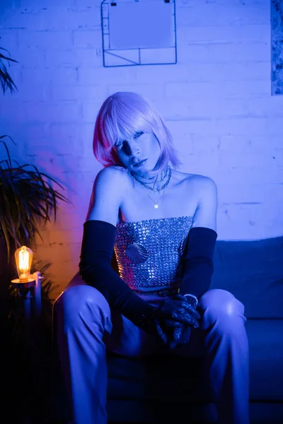 Drag Queen Parókában Nézi Kamerát Miközben Neon Fény Kanapén Otthon — Stock Fotó