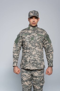 Askeri üniformalı ve şapkalı vatansever asker gri renkli yumruklarıyla ayakta duruyor. 