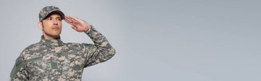 Askeri üniformalı Amerikan askeri. Anma Günü tatili boyunca şapkalı. Gri pankartta izole edilmiş. 