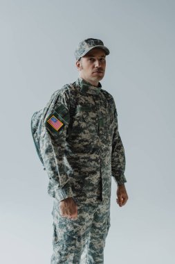 Amerikan askeri üniformalı ve ulusal bayrağı gri üzerinde duruyor. 