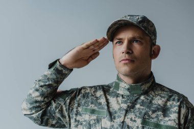 Askeri üniformalı üzgün asker. Gri üzerine izole edilmiş anma gününde selam veriyor ve ağlıyor. 