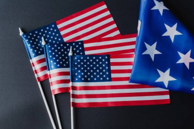 top view of three American flags near folded fabric with stars during memorial day isolated on black  clipart