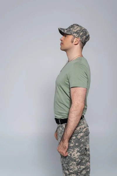 side view of soldier in t-shirt and military cap standing during memorial day isolated on grey