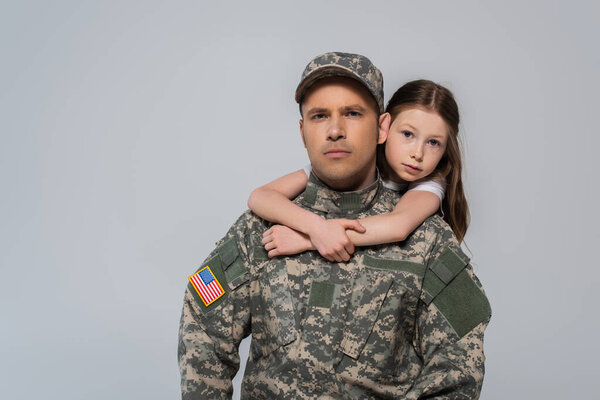 девочка-подросток, обнимающая храброго отца в военной форме в день памяти, изолированный от серых 