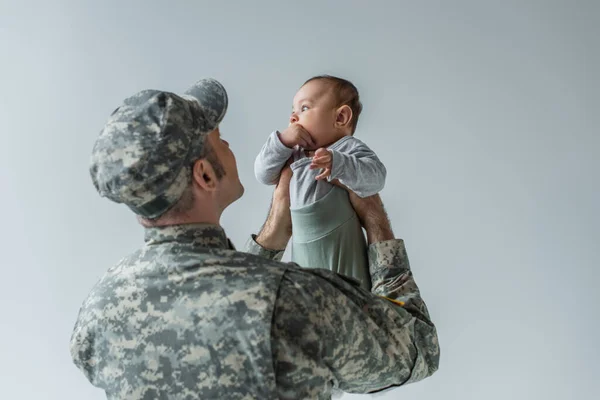 Armádní Voják Uniformě Čepice Drží Dítě Chlapce Zbraních Izolovaných Šedé — Stock fotografie