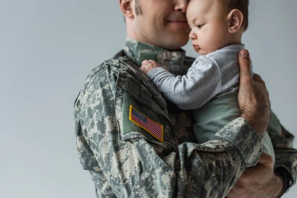 Amerykański Żołnierz Mundurze Wojskowym Trzymający Ramionach Niemowlaka Odizolowanego Szaro — Zdjęcie stockowe