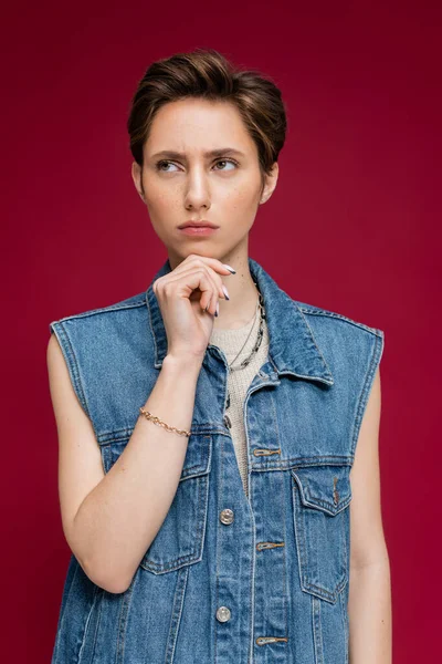 stock image pensive young woman with short hair looking away on burgundy background