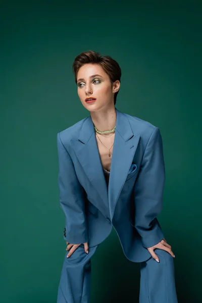 young well dressed model with short hair posing in blue suit on turquoise background