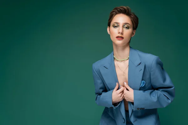 young well dressed model with short hair posing in blue blazer on turquoise background