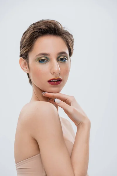 Mujer Joven Con Brillante Maquillaje Ojos Tocando Barbilla Aislada Gris —  Fotos de Stock