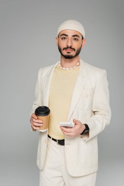 Takım elbiseli şık homoseksüel bir adam. Elinde akıllı telefon ve kahve var. Gri yolda yalnız kalmak için.  