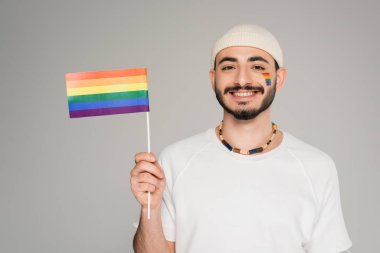 lgbt bayrağıyla pozitif gay adam gri kameraya bakıyor.  