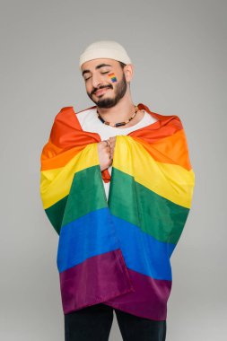 Neşeli gay adam elinde lgbt bayrağı ve kapalı gözler gri üzerine izole  