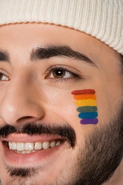 Yanağında lgbt bayrağı olan gülümseyen homoseksüel adam görüntüsü. 