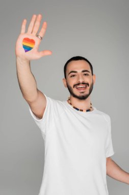 Düşüncesiz eşcinsel adam kalp şeklinde Igbt bayrağı gösteriyor. Gri, uluslararası homofobiye karşı izole bir gün.