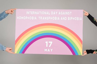Homofobiklere karşı uluslararası gün, transfobi ve bifobi yazılı levha taşıyan homoseksüel insanların gri harflerle izole edilmiş görüntüsü  