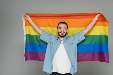 Genç homoseksüel adam elinde lgbt bayrağı tutuyordu ve kameraya bakıyordu. Gri, Uluslararası Homofobiğe Karşı Gün