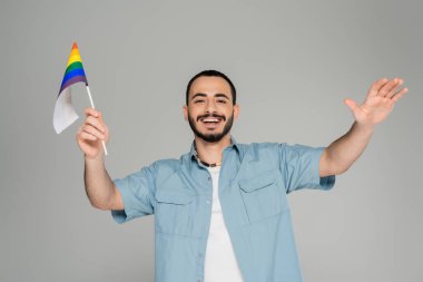 Gri, uluslararası homofobi gününde elinde lgbt bayrağı tutan pozitif ve sakallı eşcinsel bir adam.