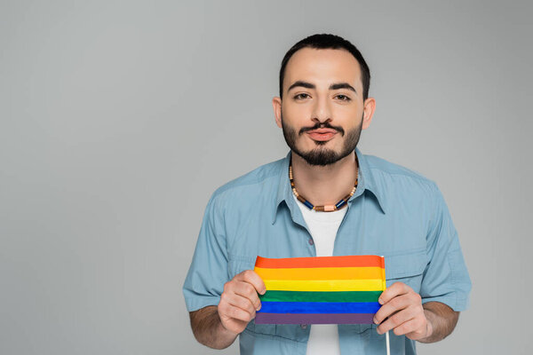 Брюнетка гей дуть губы и держа флаг lgbt изолированы на серый, Международный день борьбы с гомофобией 