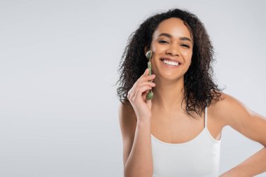 Esmer, Afro-Amerikalı bir kadın, gri renkte, yeşil bir arabasıyla yüz masajı yapıyor.