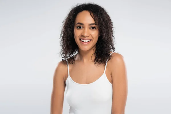Portret Beztroskiej Afroamerykanki Białej Koszulce Uśmiechniętej Kamery Odizolowanej Szaro — Zdjęcie stockowe
