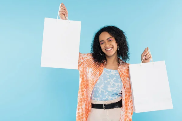 Zorgeloos Trendy Afrikaans Amerikaanse Vrouw Tonen Witte Boodschappentassen Geïsoleerd Blauw — Stockfoto
