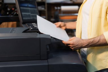 cropped view of publisher holding blank paper in print center  clipart